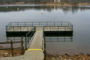 Platform dock with walkway sitting in still lake water